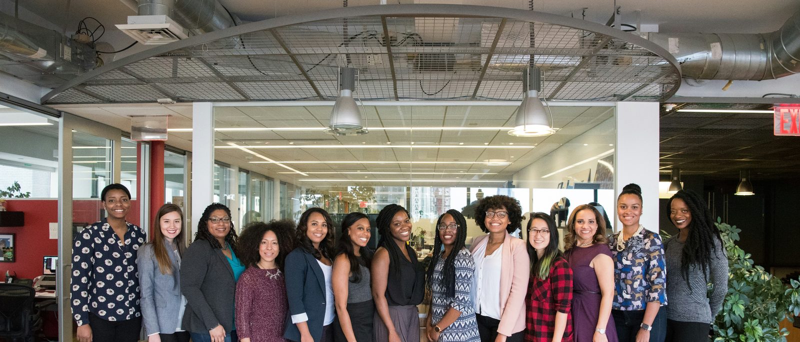 A group of women standing together in a bright office, smiling